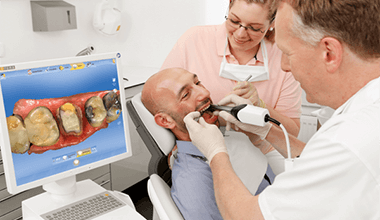 dentist taking digital scan of smiling man's teeth