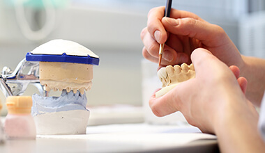 Technician fitting crown and bridge on dental mock-up