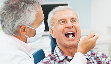 Smiling man receiving dental exam from dentist